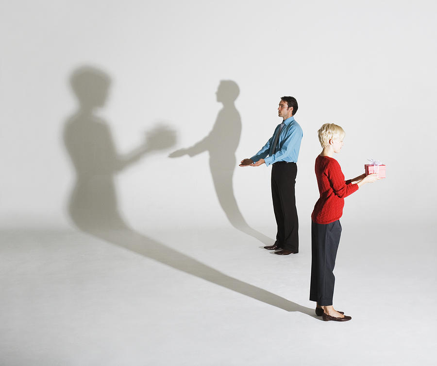 Businessman and woman standing so shadows look like shes giving him a gift Photograph by Martin Barraud