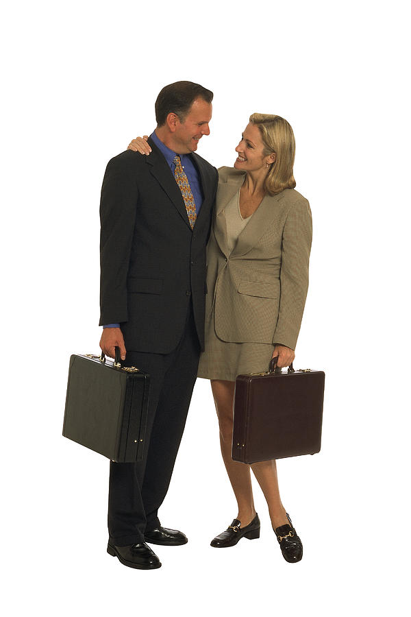 Businessman and woman with briefcases embracing Photograph by Comstock