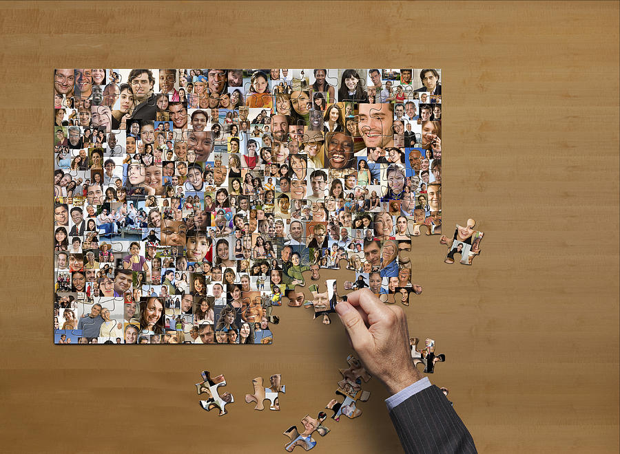 Businessman assembling puzzle of collage of smiling face Photograph by John M Lund Photography Inc