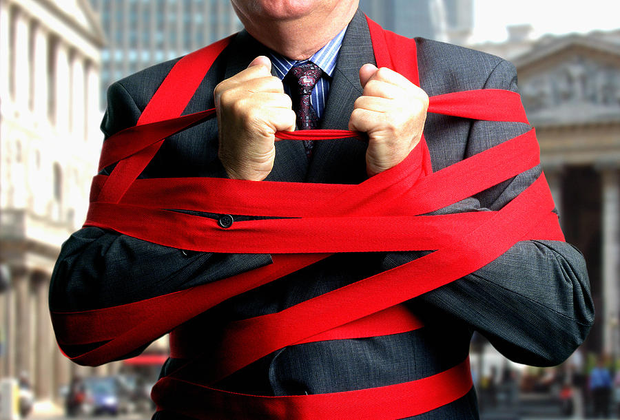 Businessman bound up in red tape, mid section, close-up Photograph by Derek Berwin