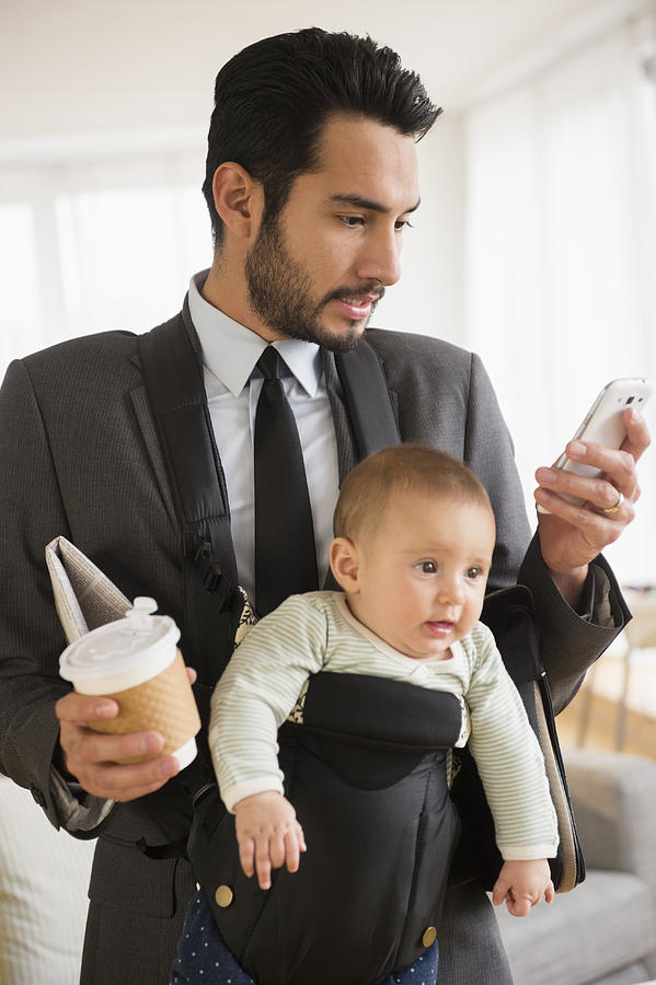 Businessman carrying baby and cell phone Photograph by JGI/Jamie Grill