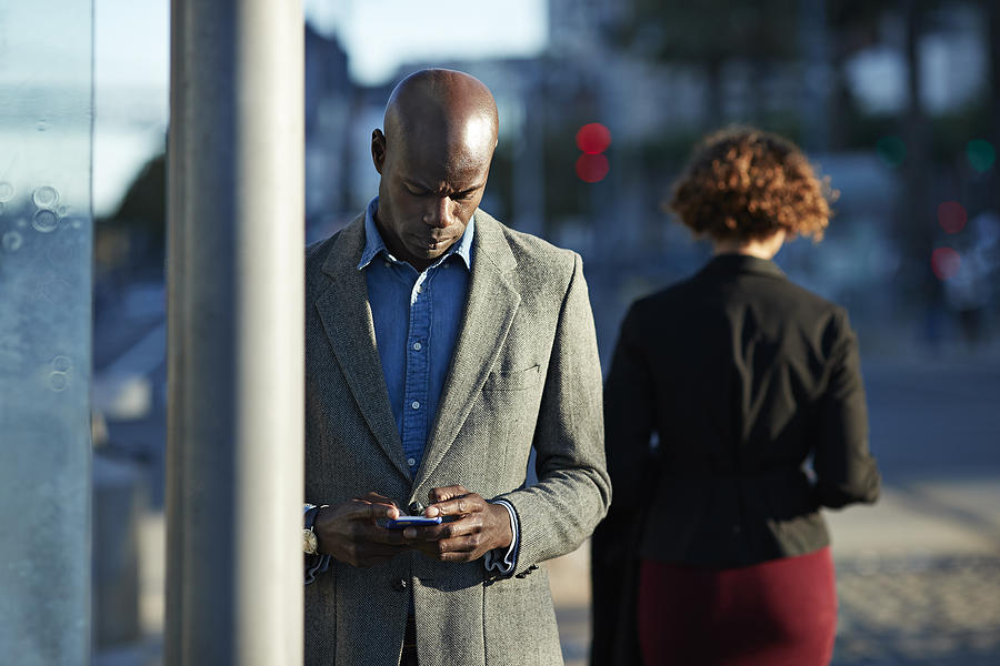 Businessman checking smartphone while waiting for the tram in San Francisco Photograph by Klaus Vedfelt