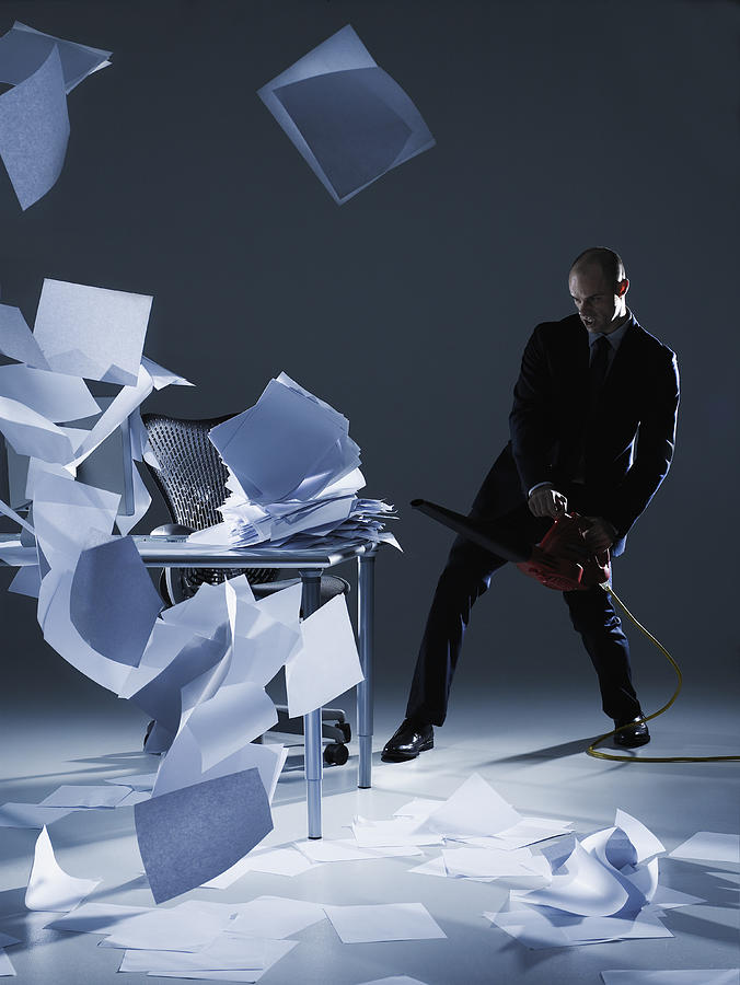 Businessman cleaning papers with leaf blower Photograph by Thomas Barwick