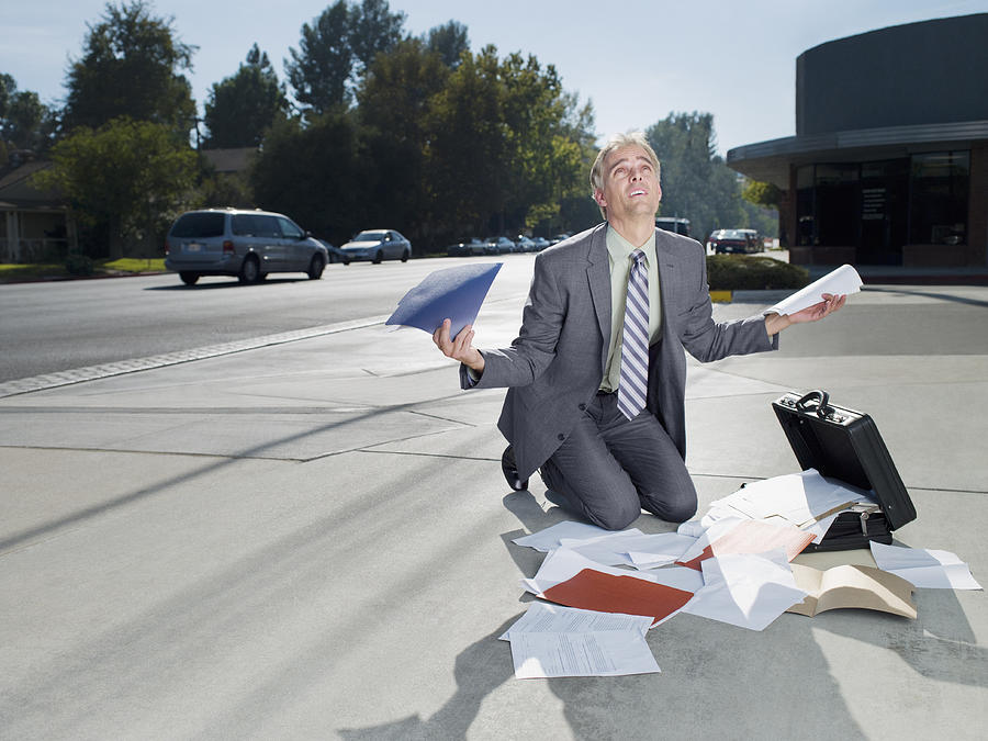 Businessman dropping papers from briefcase Photograph by Chris Ryan