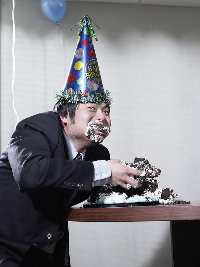 Businessman eating birthday cake with hands, stuffing face Photograph by Hans Neleman