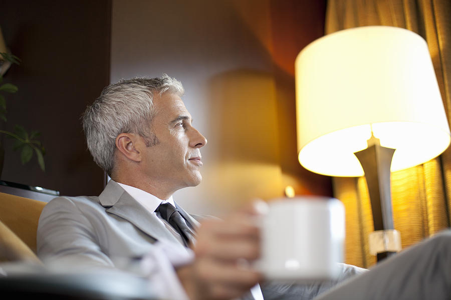 Businessman enjoys a cup of coffee. Photograph by Assembly