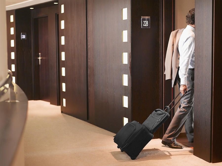 Businessman entering hotel room with suitcase Photograph by Robert Daly