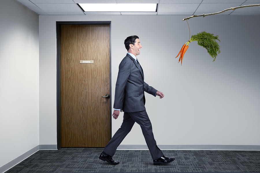 Businessman Following Dangling Carrot In Office Photograph by Dny59