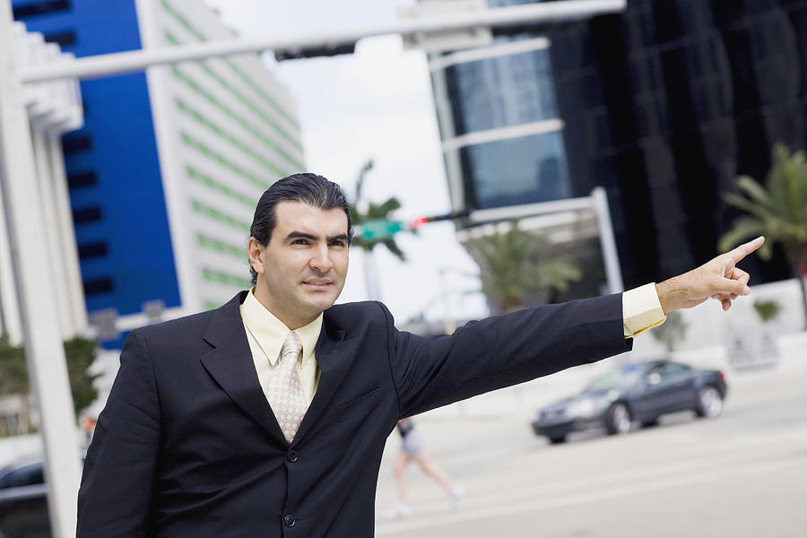 Businessman hailing a vehicle Photograph by Glowimages