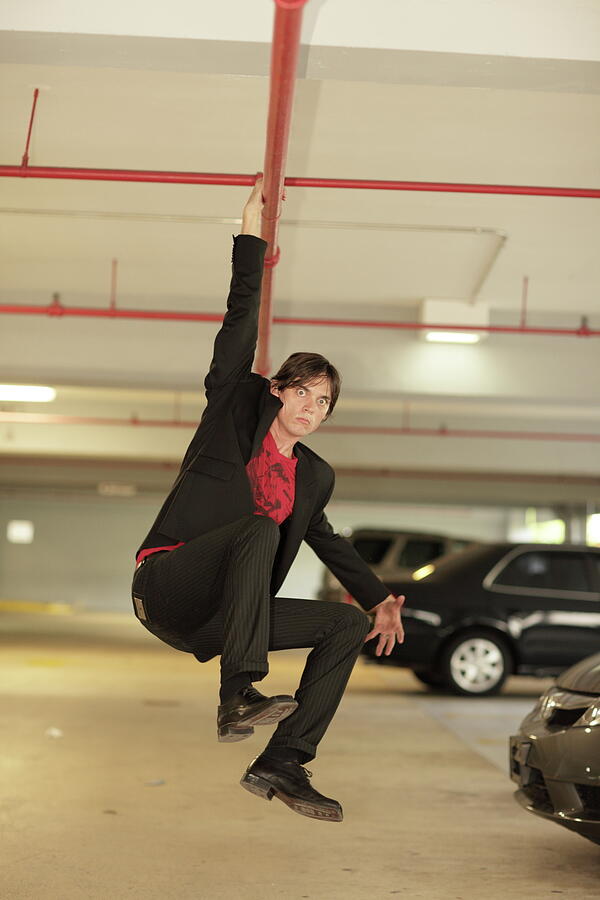 Car Photograph - Businessman hanging around from a red metal pipe by Felix Mizioznikov