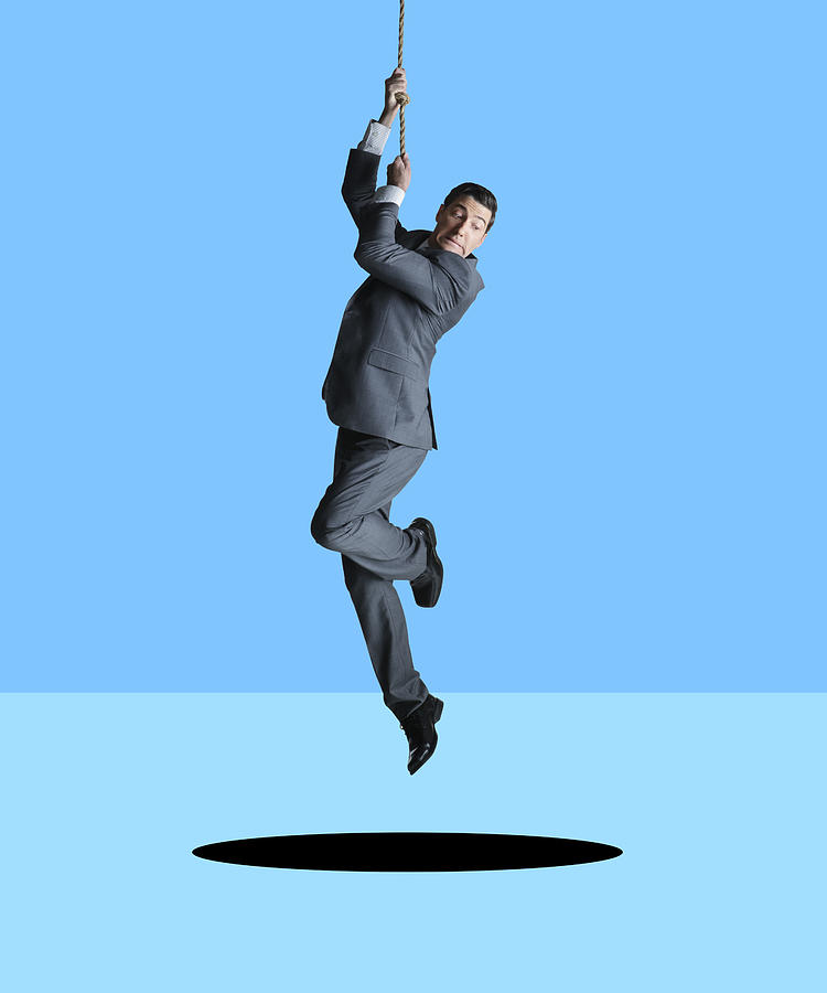 Businessman Hanging From Rope Looks Down At Hole Photograph by Dny59