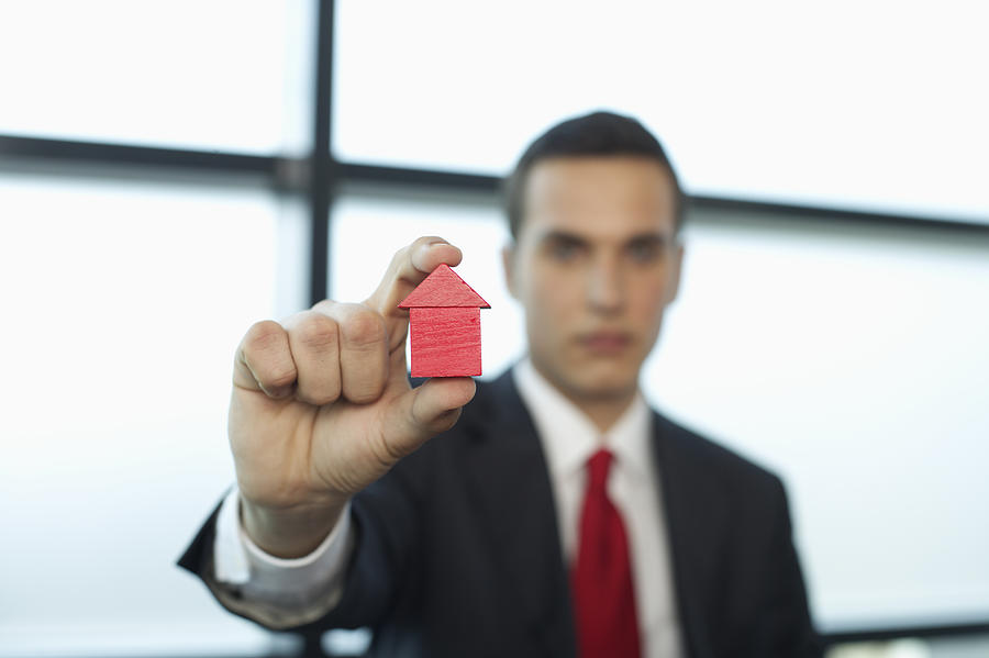 Businessman holding a model house between fingers Photograph by Stock4b-rf