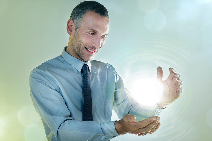 Businessman holding ball of light Photograph by Image Source