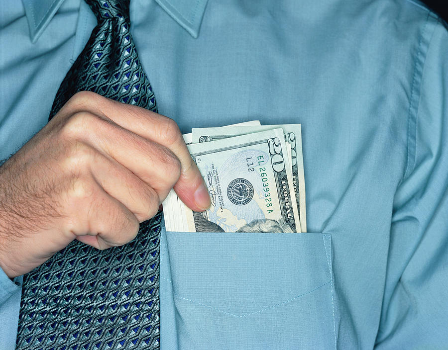 Businessman holding twenty dollar notes in shirt pocket, close-up Photograph by Peter Dazeley