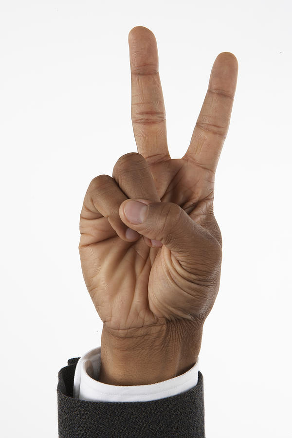 Businessman holding up two fingers (focus on hand) Photograph by Thomas Northcut