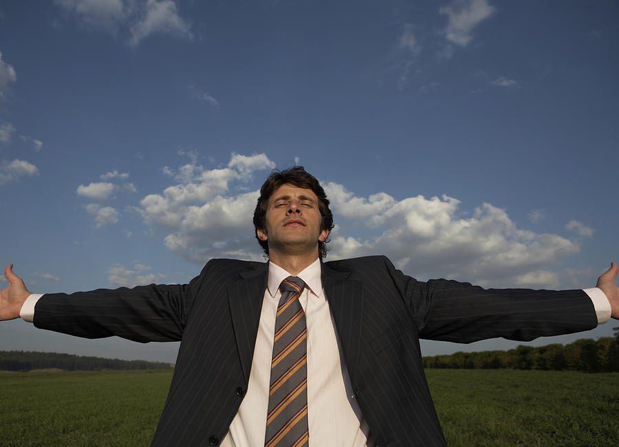 Businessman in field spreading arms wide Photograph by Baoba Images