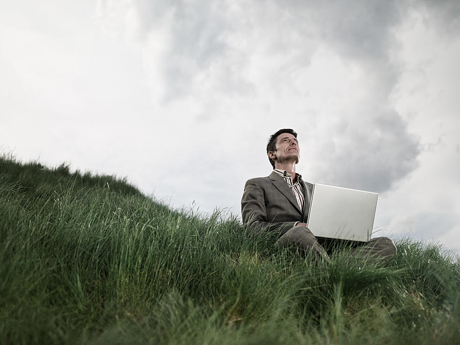 Businessman in field with laptop Photograph by Image Source