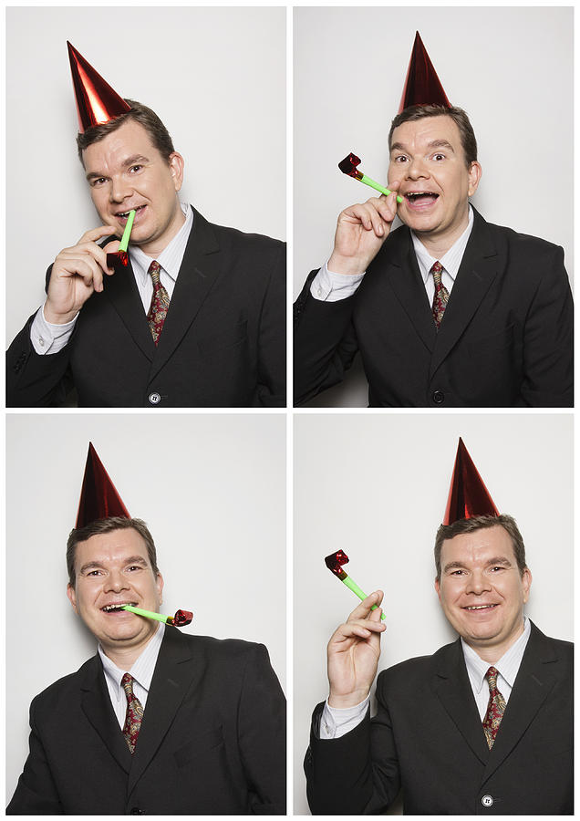 Businessman in photo booth wearing party hat Photograph by Compassionate Eye Foundation/Chris Windsor