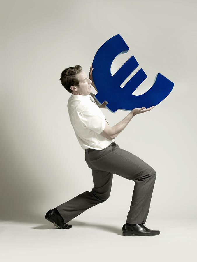 Businessman lifting large Euro symbol Photograph by Flashpop