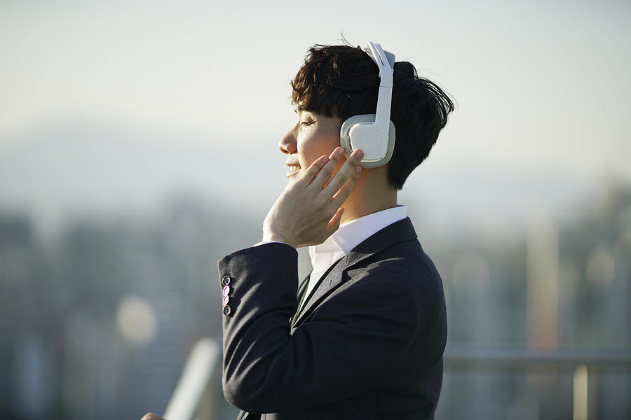 Businessman listening music on rooftop Photograph by Runstudio