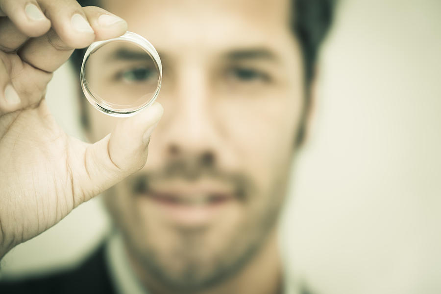 Businessman looking through a round lens Photograph by Caracterdesign