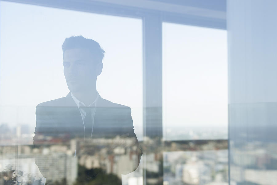 Businessman looking through window Photograph by PhotoAlto/Ale Ventura