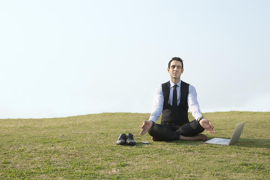 Businessman meditating outdoors , INDIA , DELHI Photograph by IndiaPix/IndiaPicture