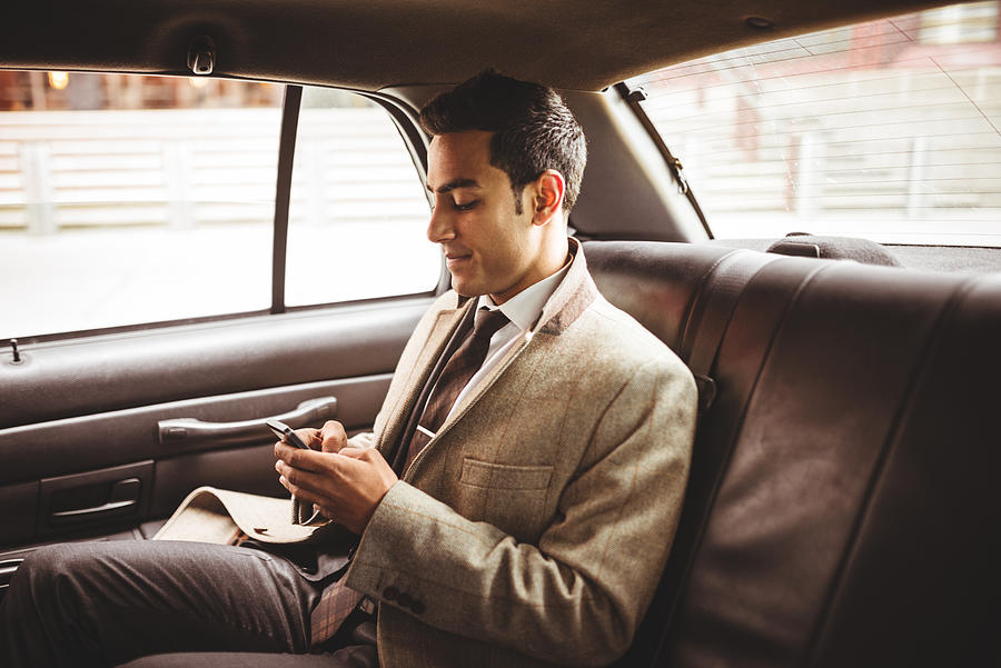 Businessman on a yellow cab text messaging Photograph by Franckreporter