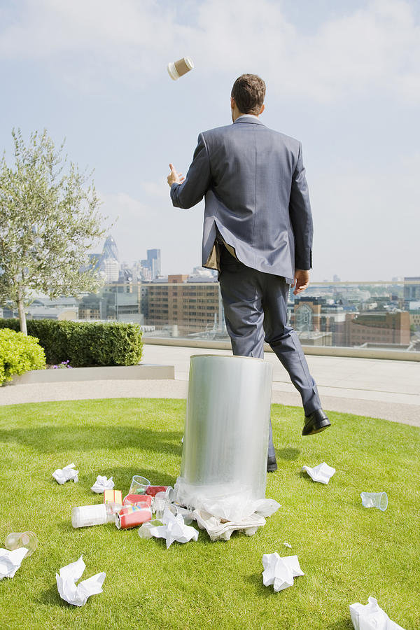 Businessman on rooftop by dustbin, rear view Photograph by Justin Pumfrey