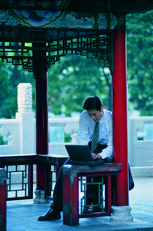 Businessman outside on laptop computer Photograph by Photodisc