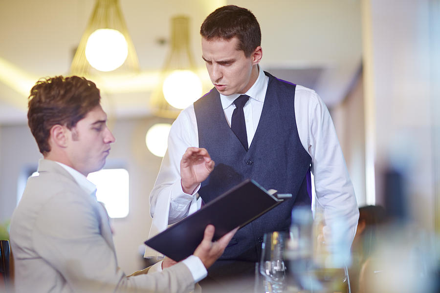 Businessman placing an order with waiter at hotel restaurant Photograph by Westend61