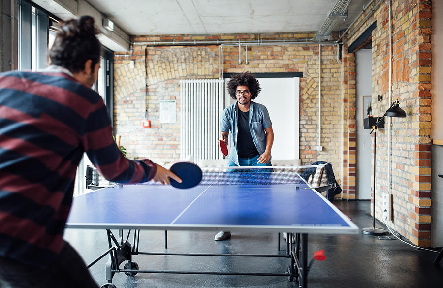 Businessman playing table tennis with colleague Photograph by Luis Alvarez
