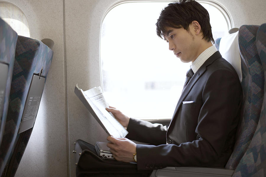 Businessman Reading a Paper on a Train Photograph by Digital Vision.