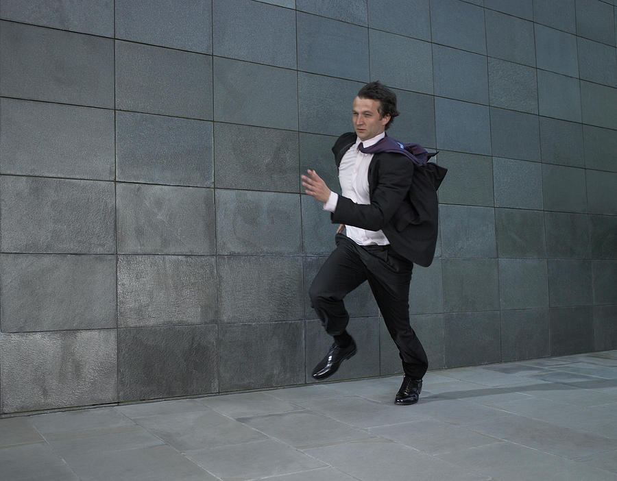 Businessman running against wind Photograph by Michael Blann