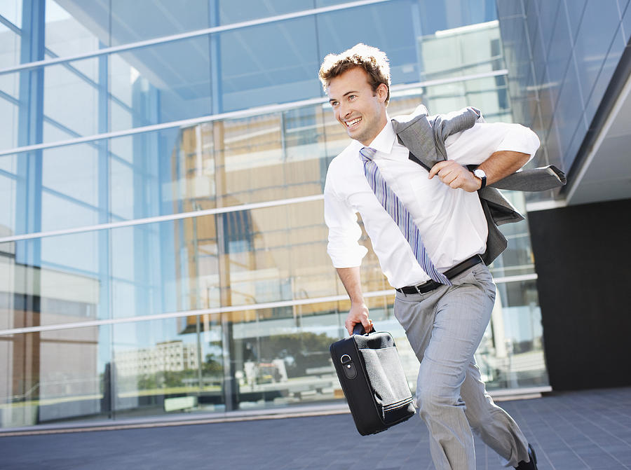 Businessman running with briefcase Photograph by Paul Bradbury