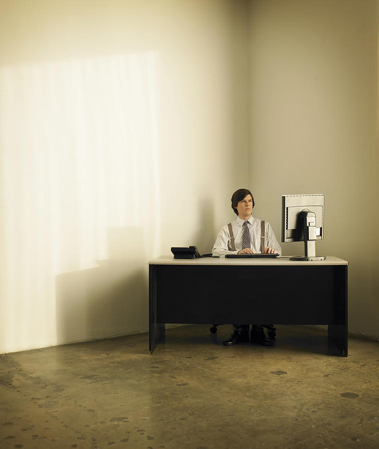 Businessman sitting at desk in corner Photograph by Siri Stafford