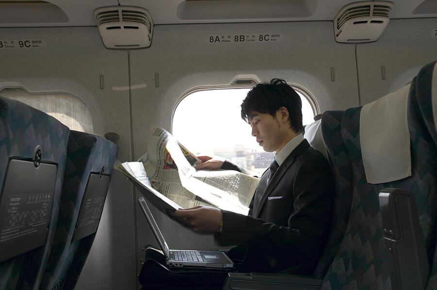 Businessman Sitting in a Passenger Train and Reading a Newspaper Photograph by Digital Vision.