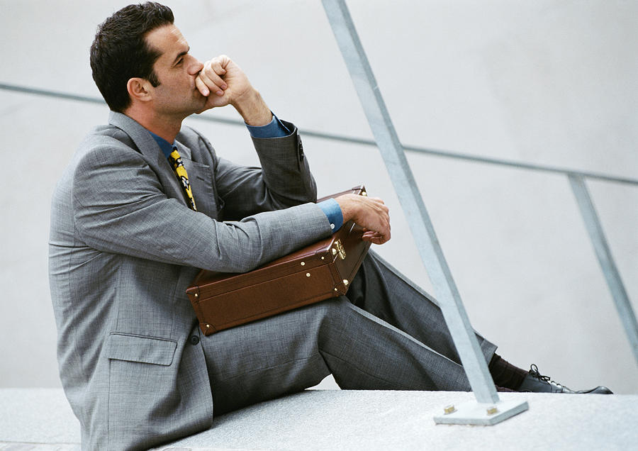 Businessman sitting on stairs, holding briefcase Photograph by Eric Audras