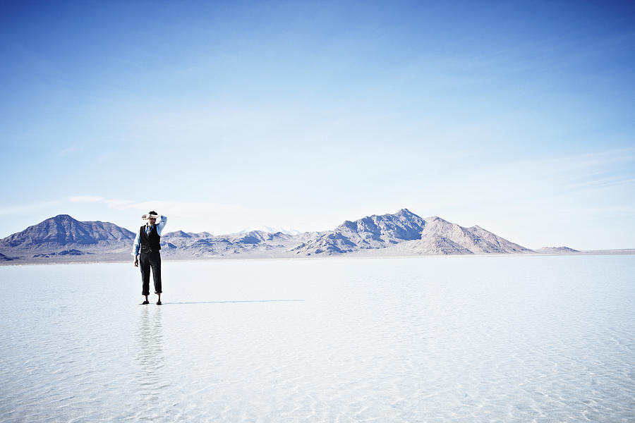 Businessman standing alone in shallow water Photograph by Thomas Barwick