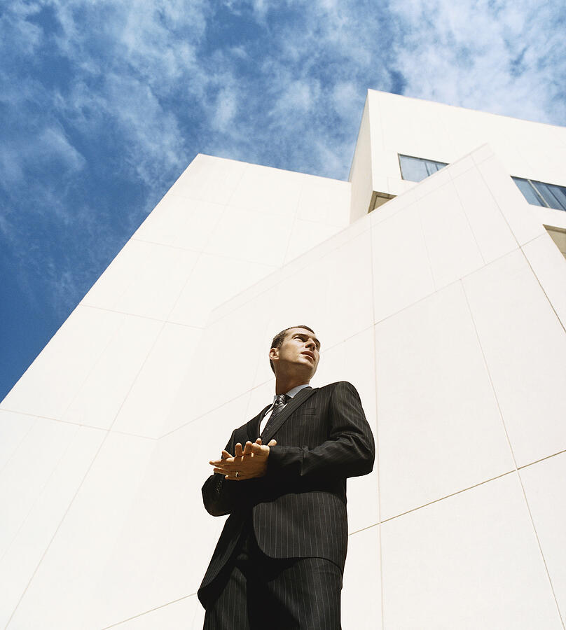 Businessman Standing in Front of an Office Building With His Hands Together Photograph by Digital Vision.