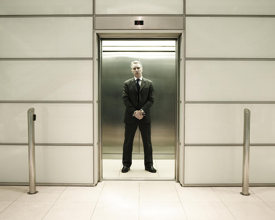 Businessman standing in office lift Photograph by Flashpop