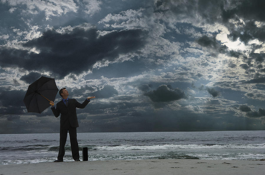 Businessman Standing on a Beach at Night, Looking Up From  an Umbrella and Checking for Rain Photograph by John Cumming