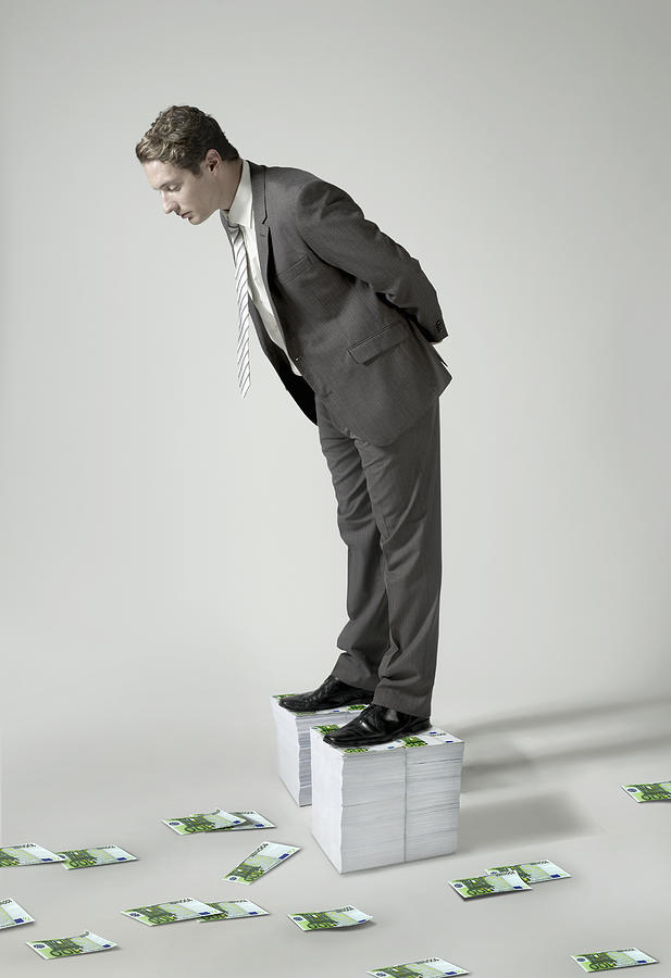 Businessman standing on large pile of Euro notes Photograph by Flashpop