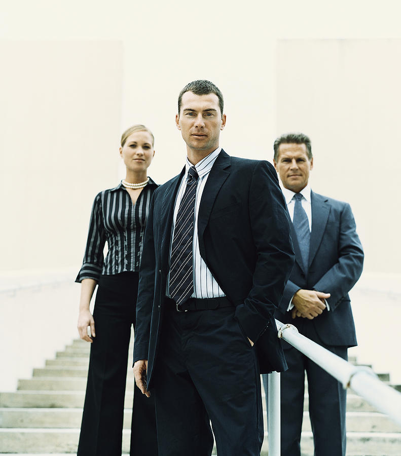 Businessman Standing on Steps in Front of Two Other Business Executives Photograph by Digital Vision.