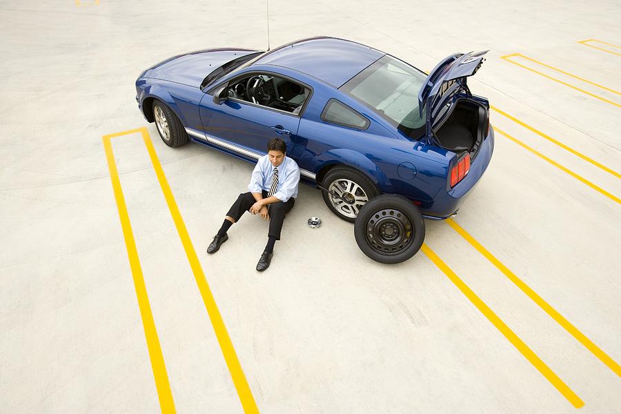 Businessman stranded with a flat tire Photograph by Fuse