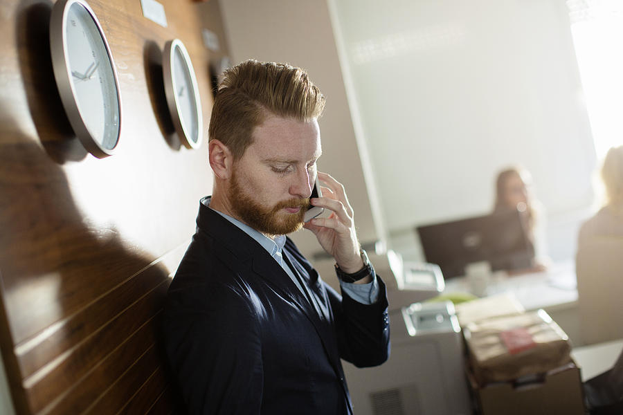 Businessman talking on phone in the office Photograph by Milanvirijevic