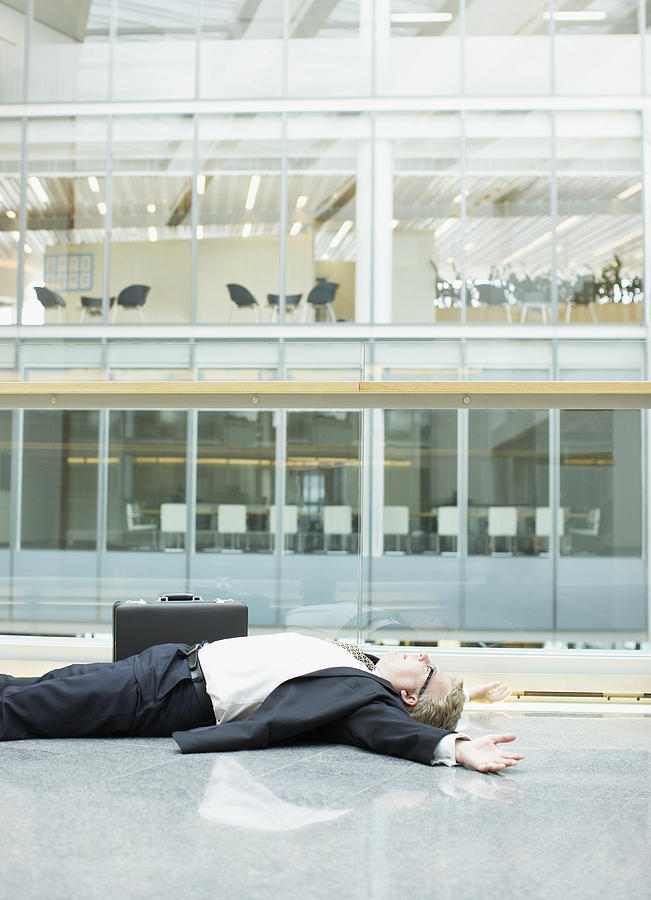 Businessman unconscious in building lobby Photograph by Paul Bradbury