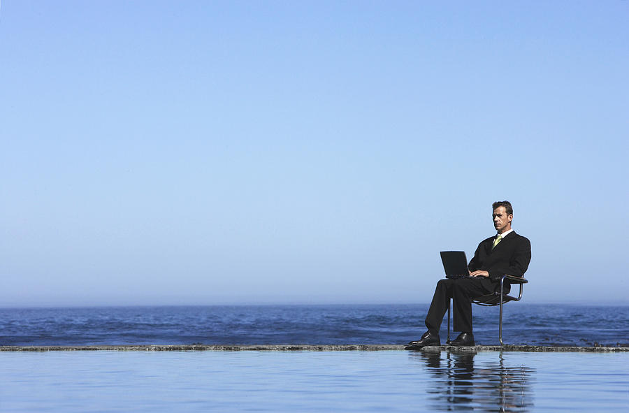Businessman Using a Laptop Computer by the Sea Photograph by John Cumming