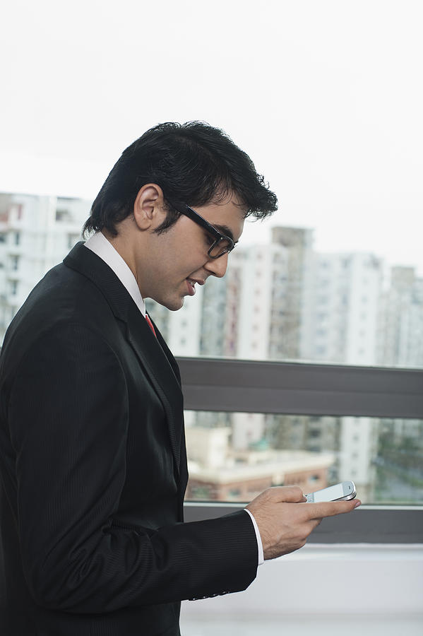 Businessman using a mobile phone Photograph by Uniquely India
