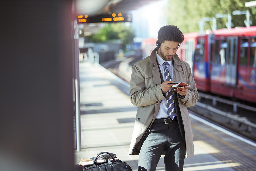 Businessman using cell phone in train station Photograph by Caia Image